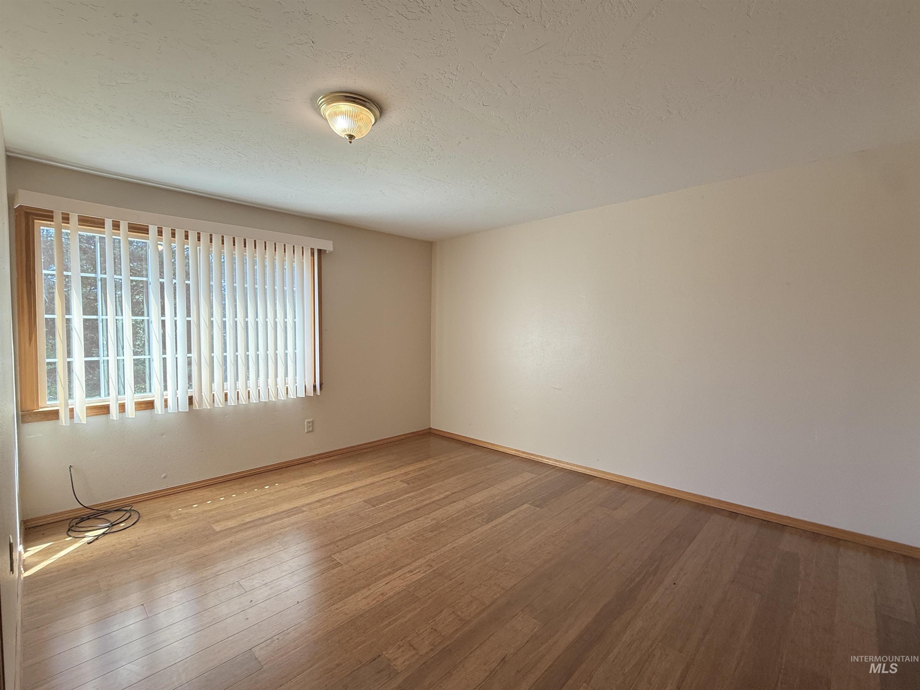 Empty room featuring hardwood / wood-style floors and a textured ceiling