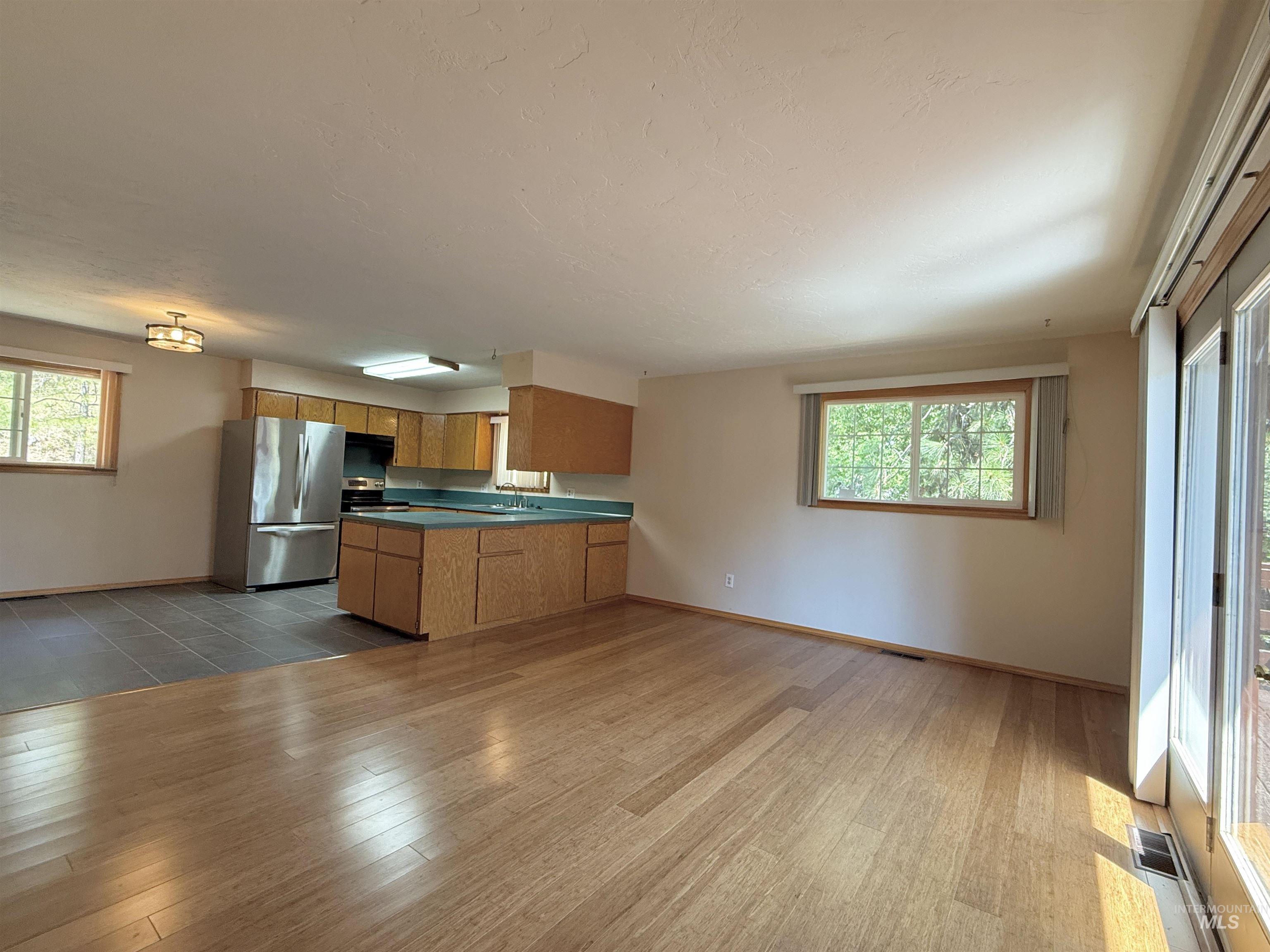 Kitchen with a peninsula, stainless steel appliances, light wood-style floors, dark countertops, and open floor plan