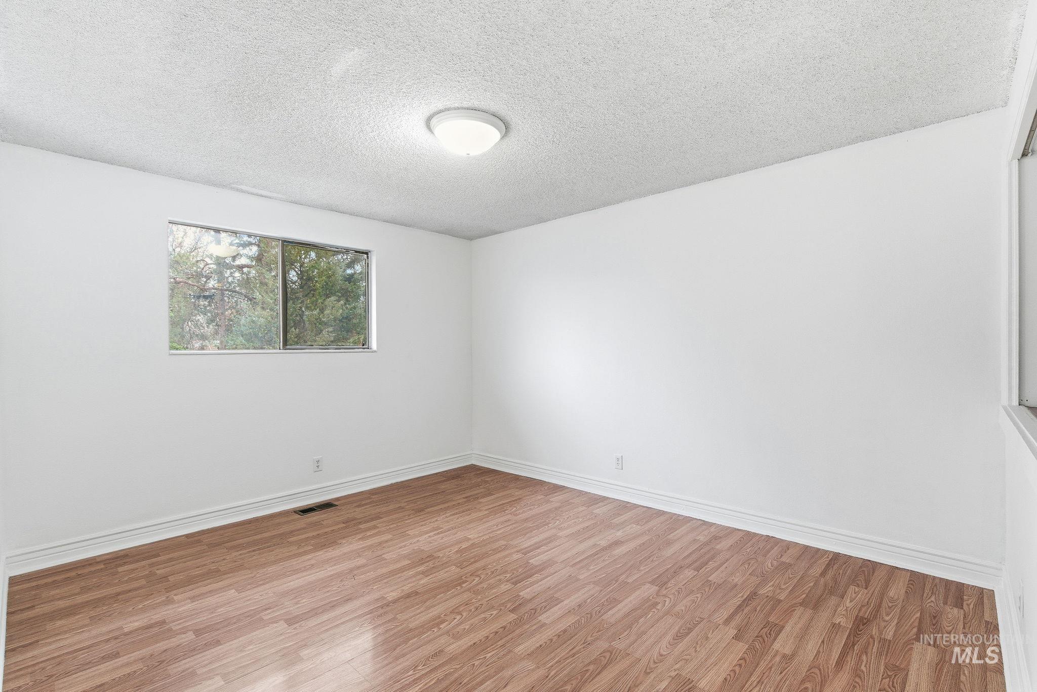 Empty room with a textured ceiling and wood finished floors