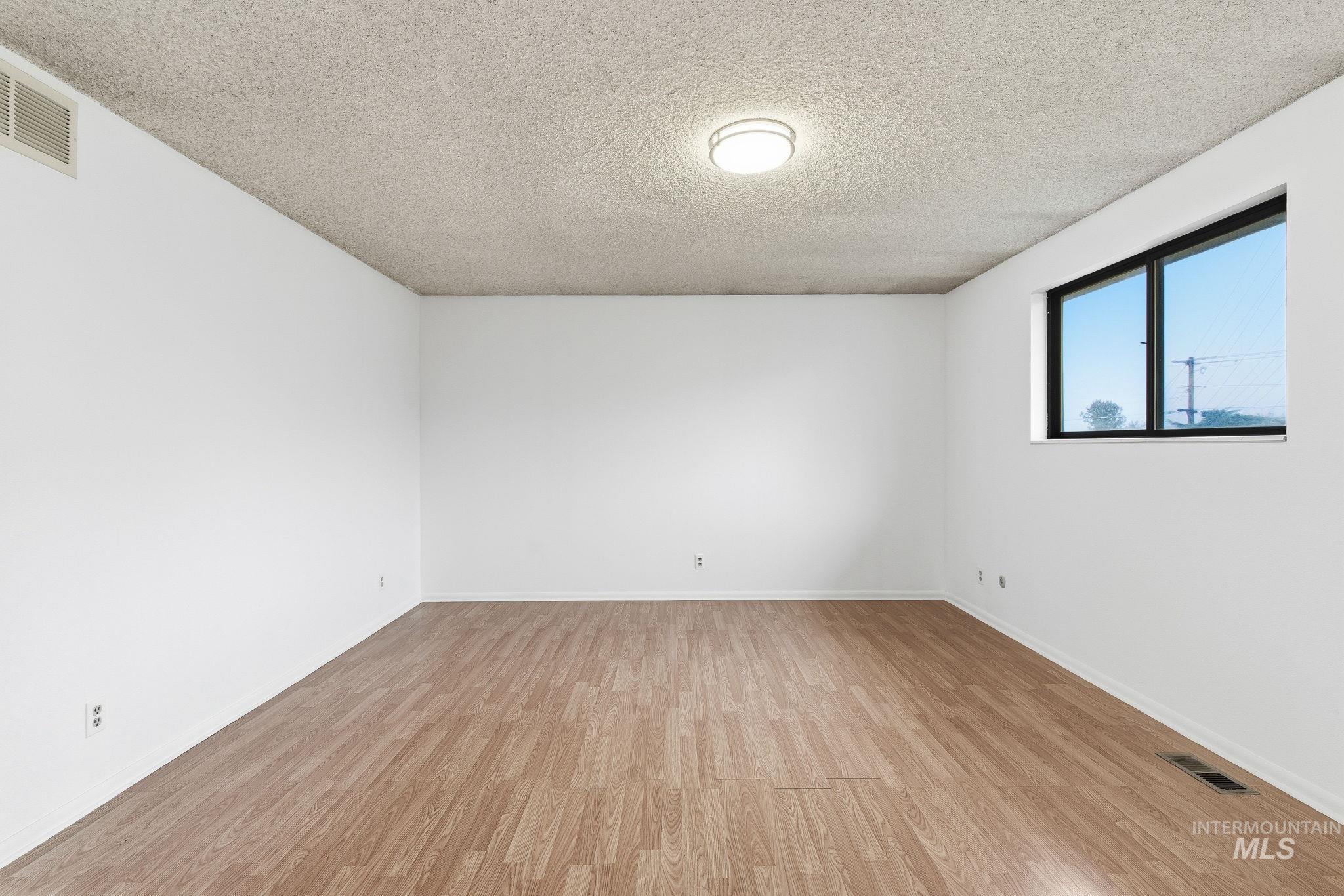 Empty room featuring a textured ceiling and light wood finished floors