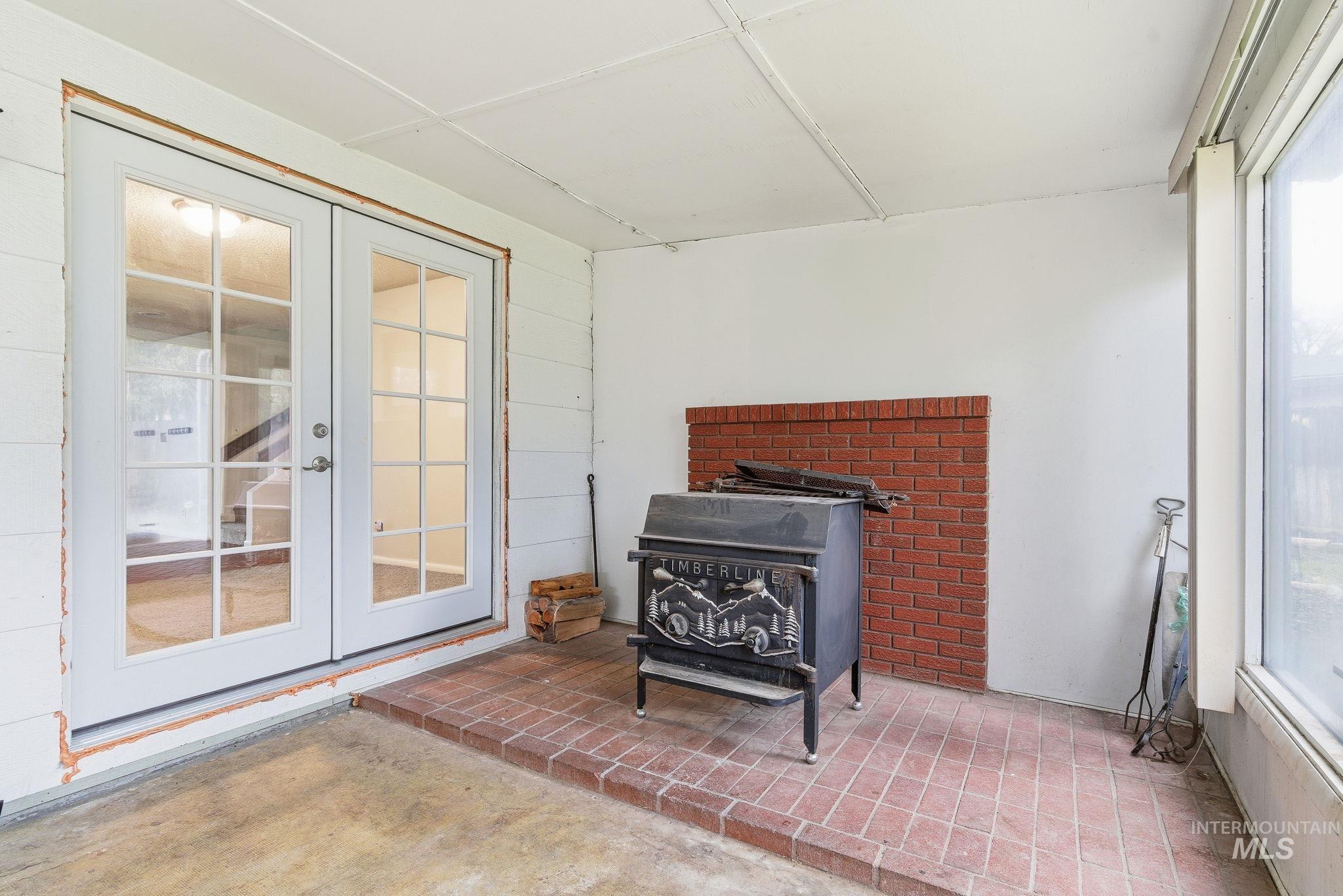 Sunroom / solarium featuring french doors and a wood stove