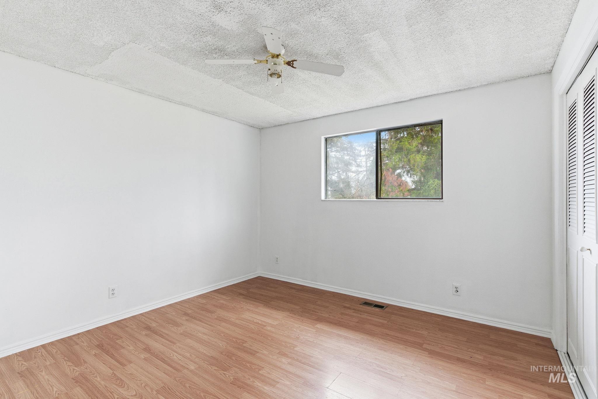Unfurnished bedroom with a textured ceiling, ceiling fan, light wood finished floors, and a closet