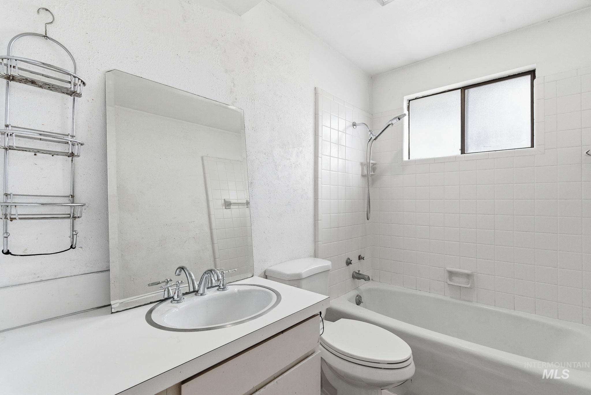 Bathroom with bathing tub / shower combination, vanity, and a textured wall