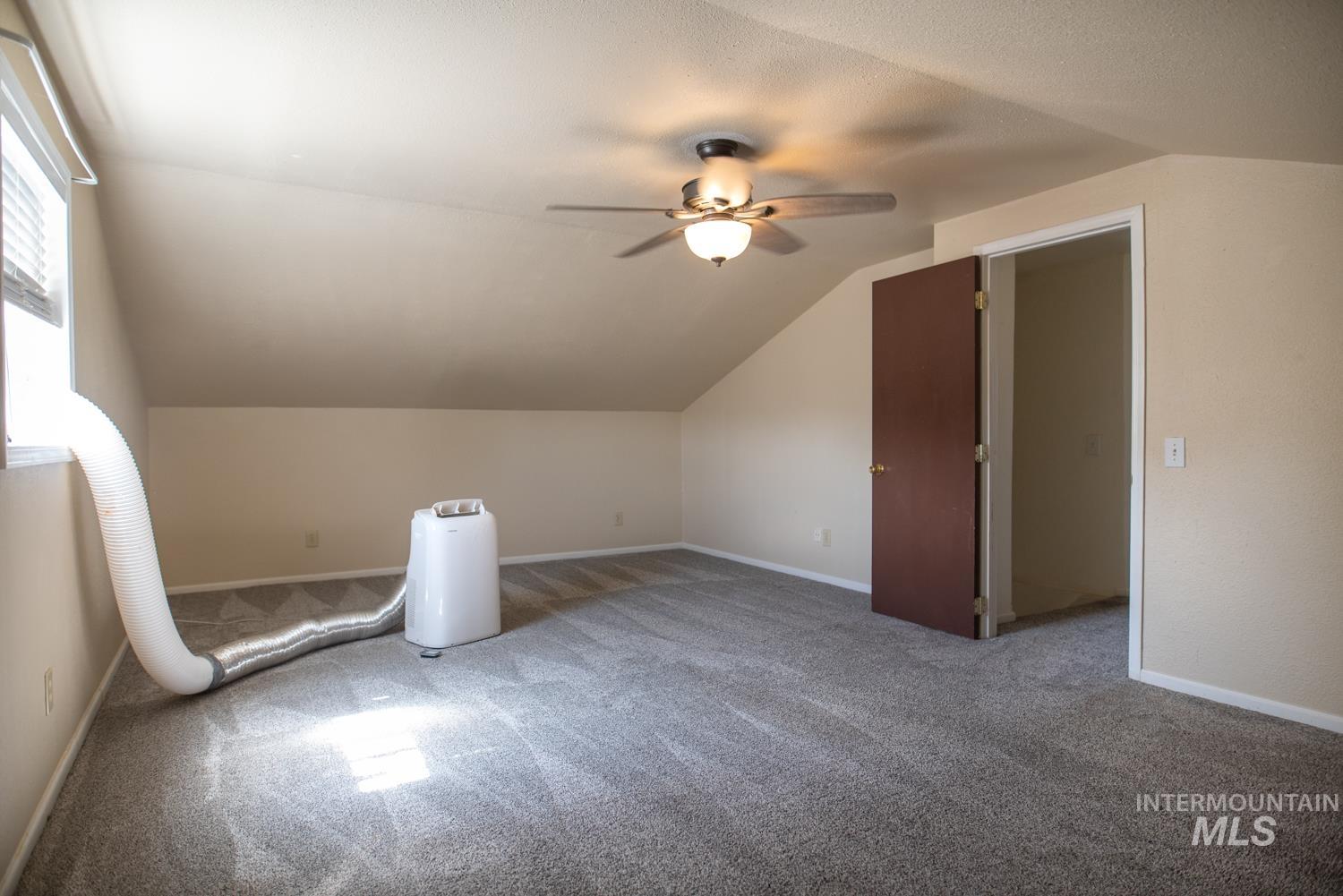 Additional living space featuring carpet, lofted ceiling, and ceiling fan