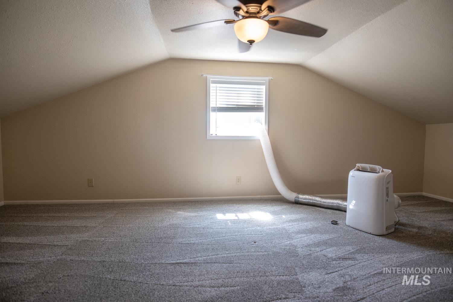 Bonus room with carpet floors, vaulted ceiling, ceiling fan, and a textured ceiling
