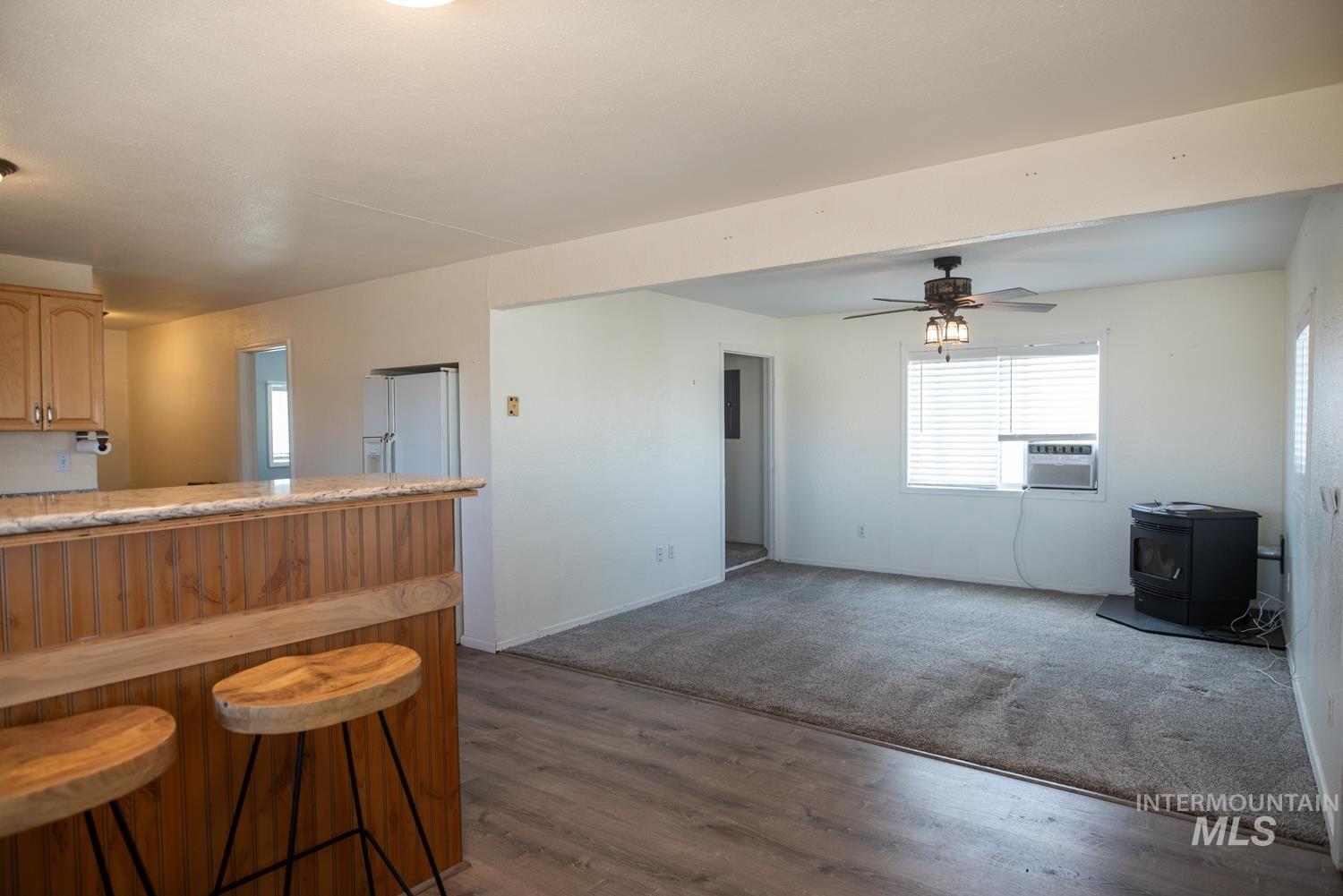 Kitchen featuring a wood stove, light countertops, a breakfast bar, white refrigerator with ice dispenser, and dark wood-style floors
