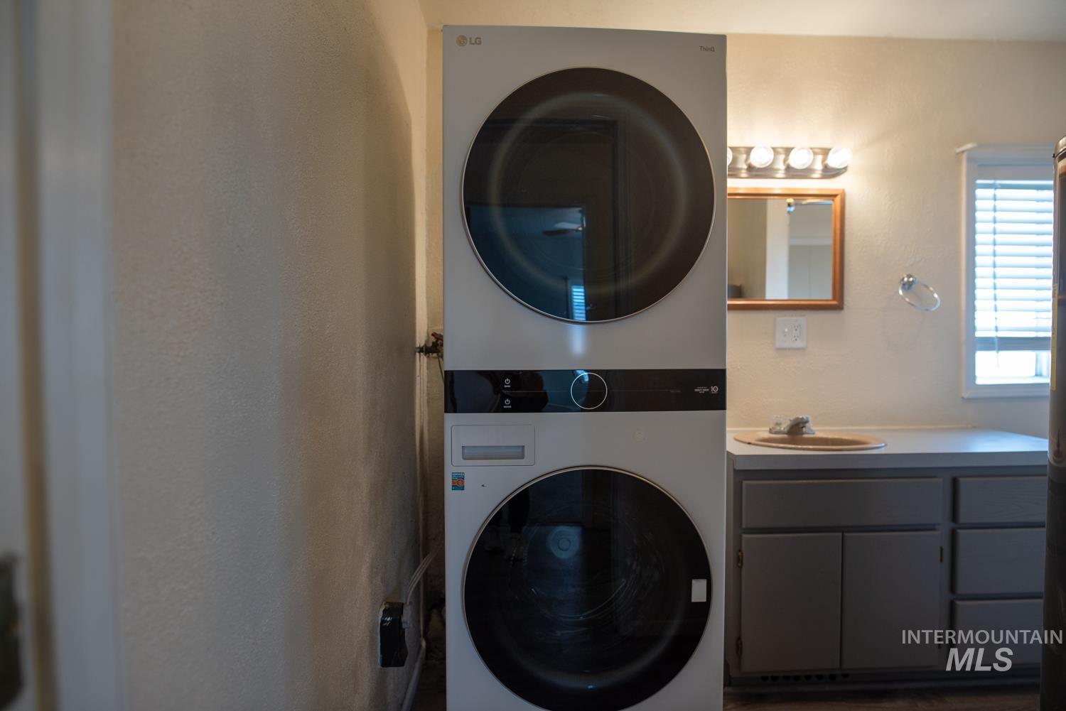Laundry room featuring estacked washer and dryer and a sink