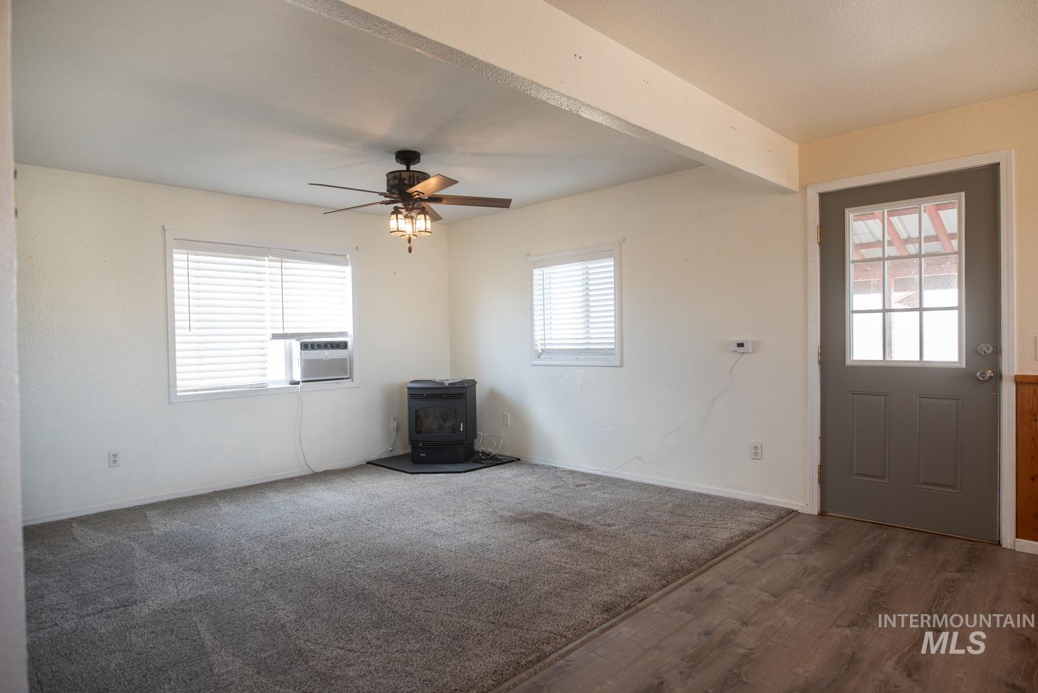 Entrance foyer featuring a wood stove, ceiling fan, wood finished floors, and cooling unit