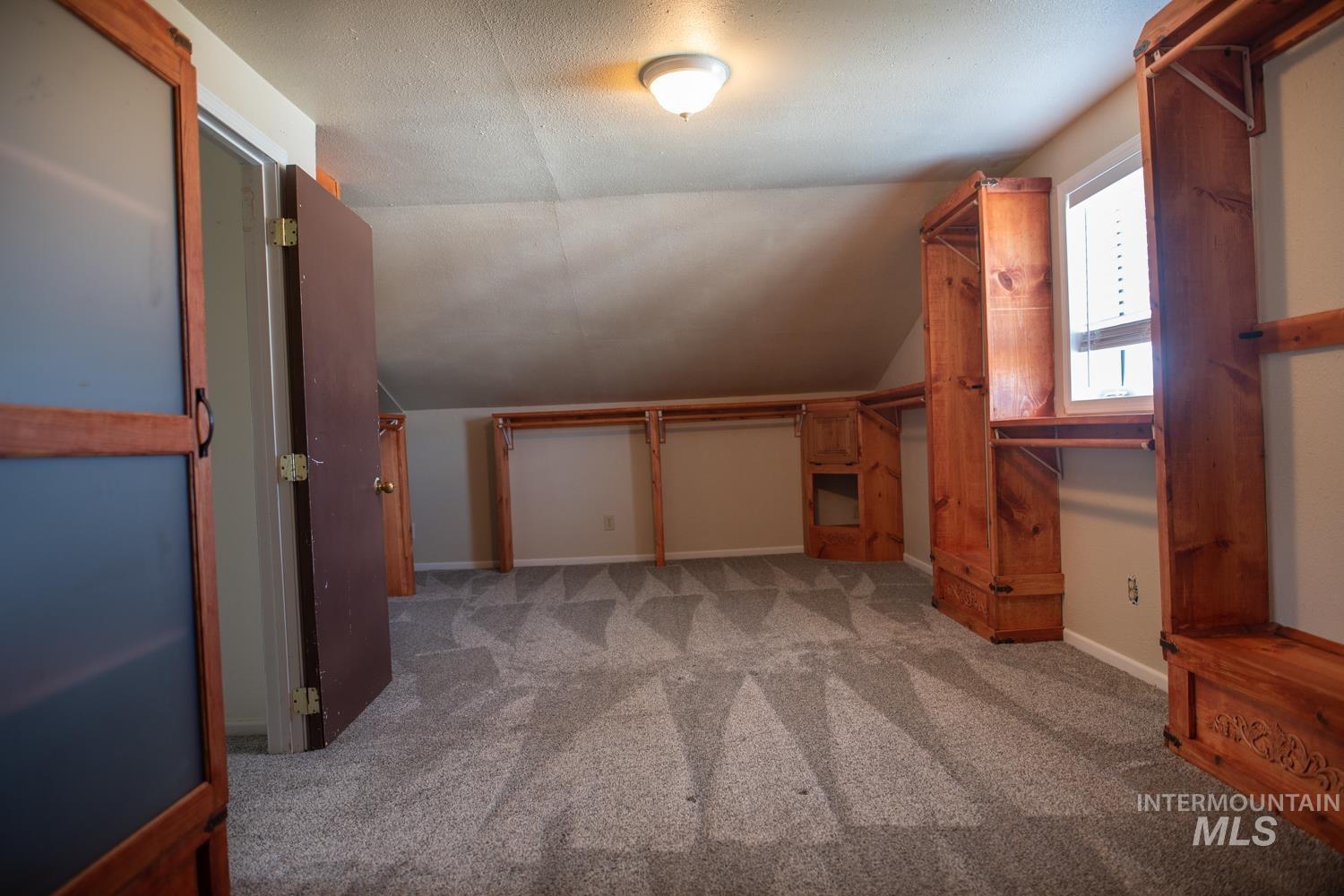 Additional living space with vaulted ceiling and light colored carpet