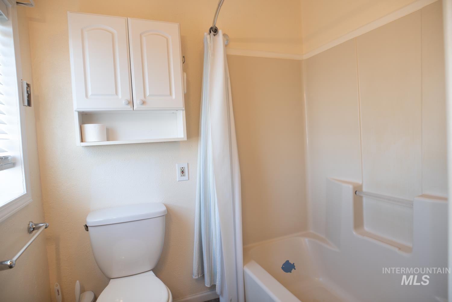 Bathroom featuring toilet and shower / bath combination with curtain