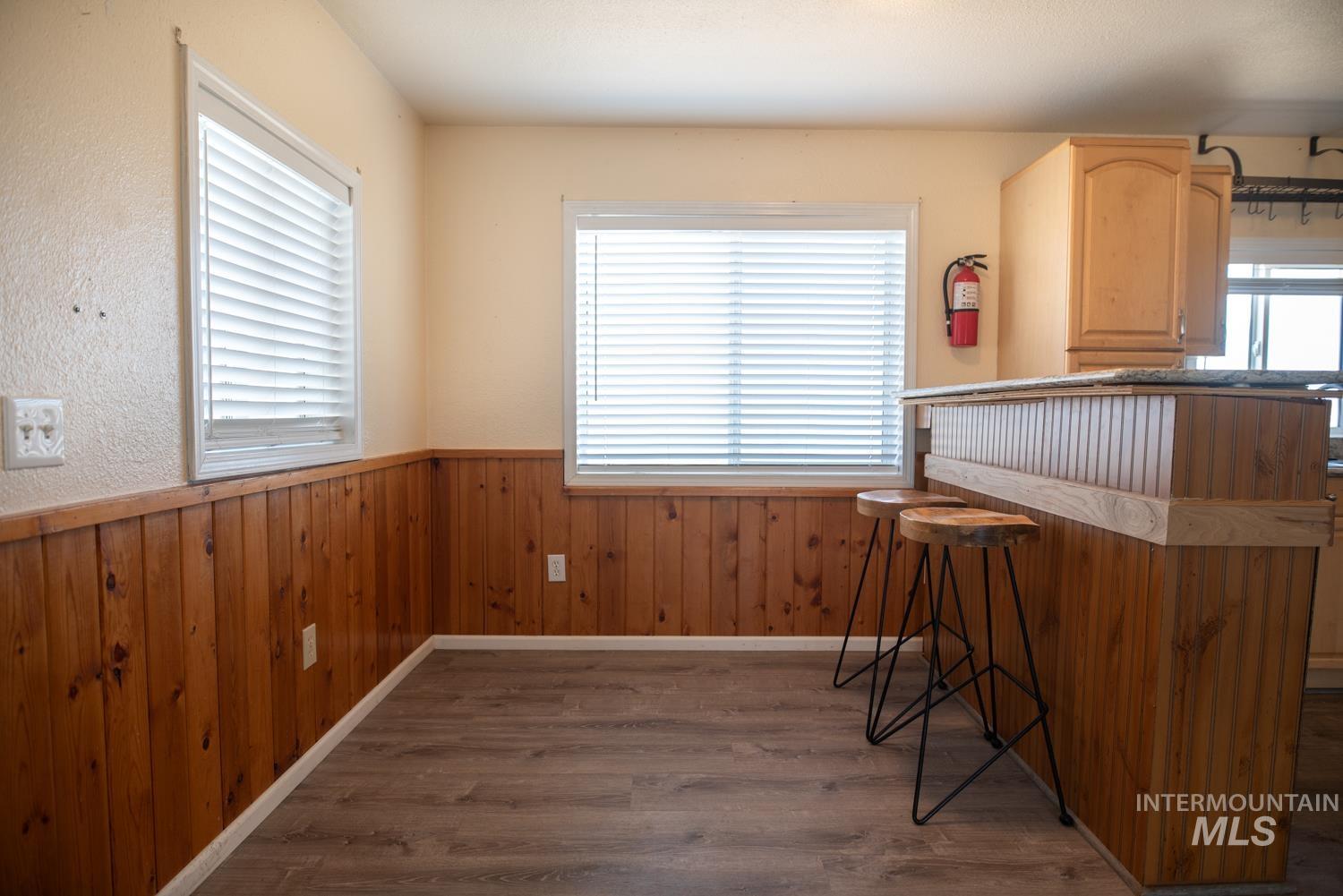 Unfurnished dining area with wood finished floors, a wainscoted wall, and wooden walls