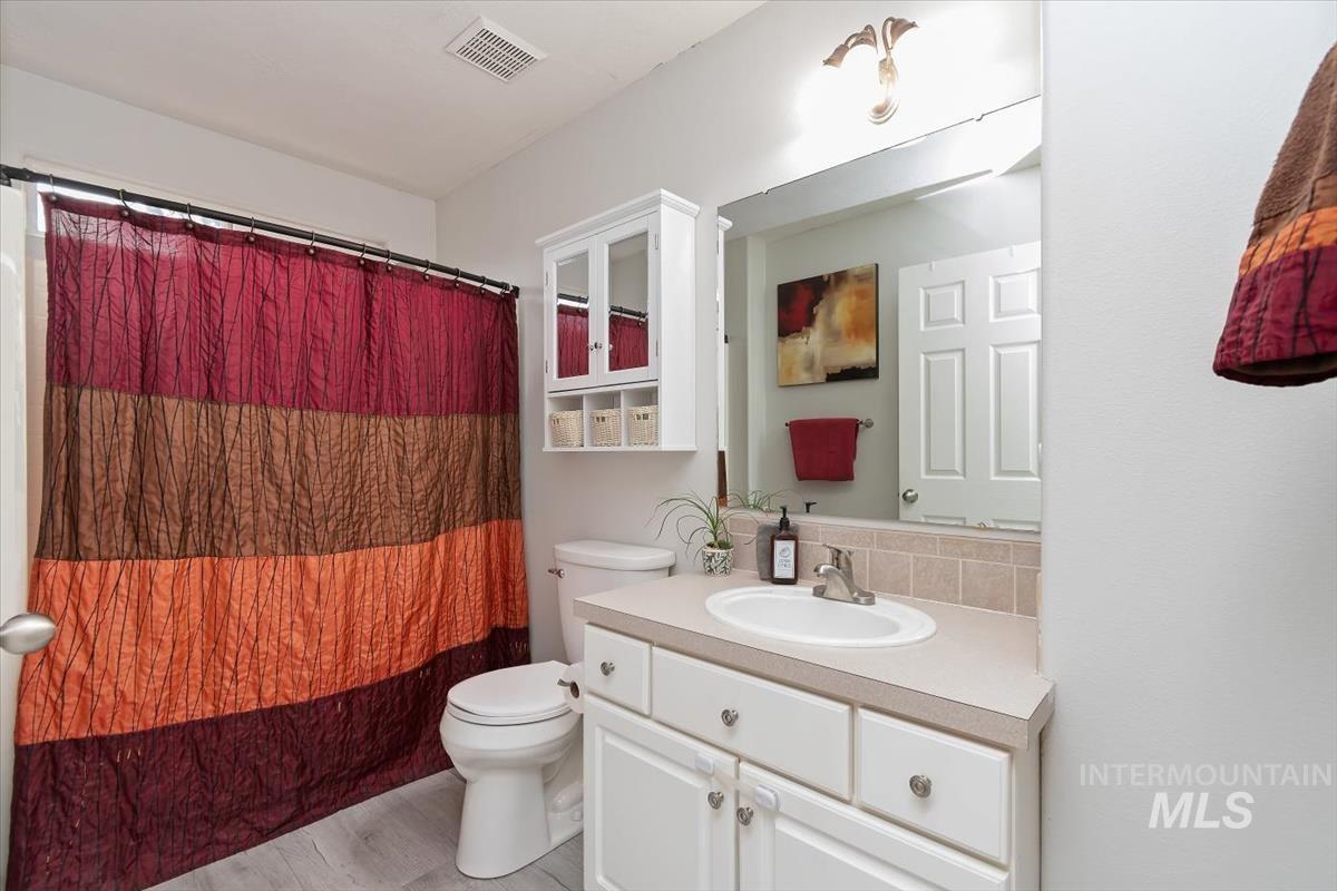 Bathroom featuring a single vanity with an integrated sink, light-toned countertop, and white cabinetry