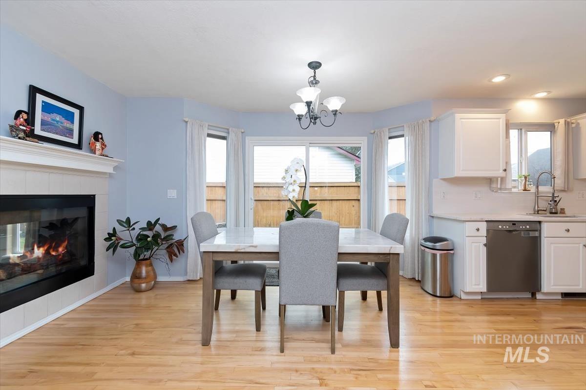 Dining area featuring a tiled fireplace with mantel, sliding glass door access to the exterior, hardwood flooring, and a chandelier