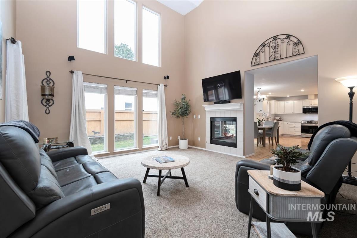 Living area featuring vaulted ceilings, a fireplace with a white mantel, and large picture windows