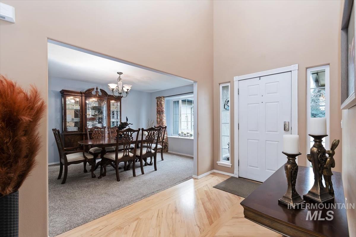 Entryway with a light wood-finish herringbone floor pattern and a paneled front door framed by two narrow sidelight windows