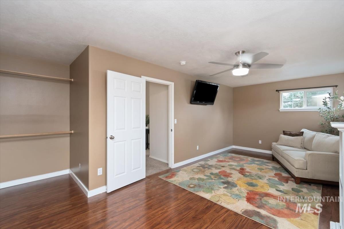 Spacious room featuring wood-finish flooring, a ceiling fan, and a window with natural light