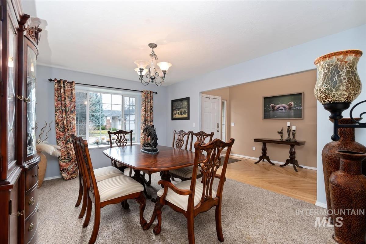 Dining area featuring light carpeting, a large window, and an overhead chandelier light fixture