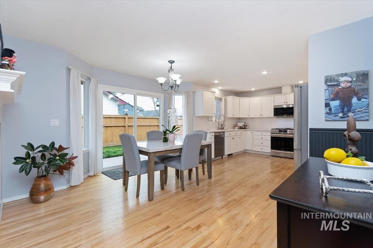 Open-concept kitchen and dining area featuring light wood-finish flooring, white cabinetry, stainless steel appliances, and recessed lighting