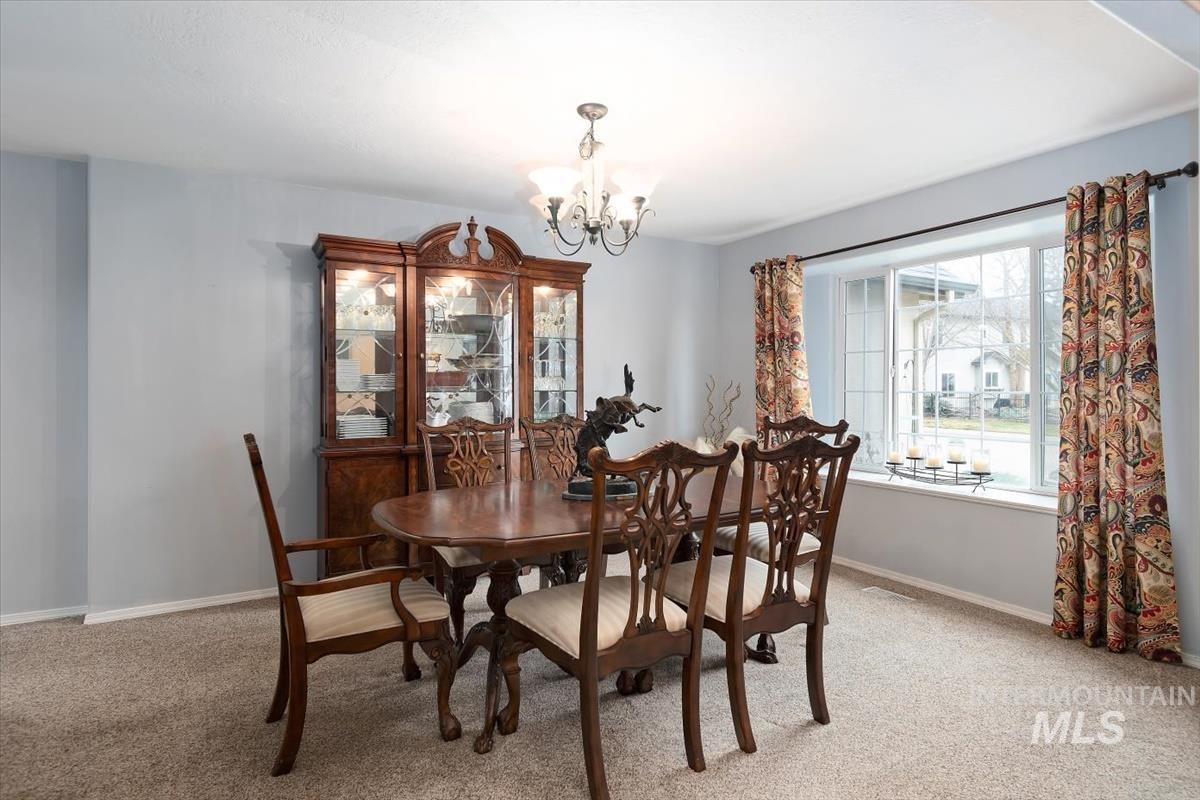 Spacious dining area featuring neutral carpeting and light blue walls