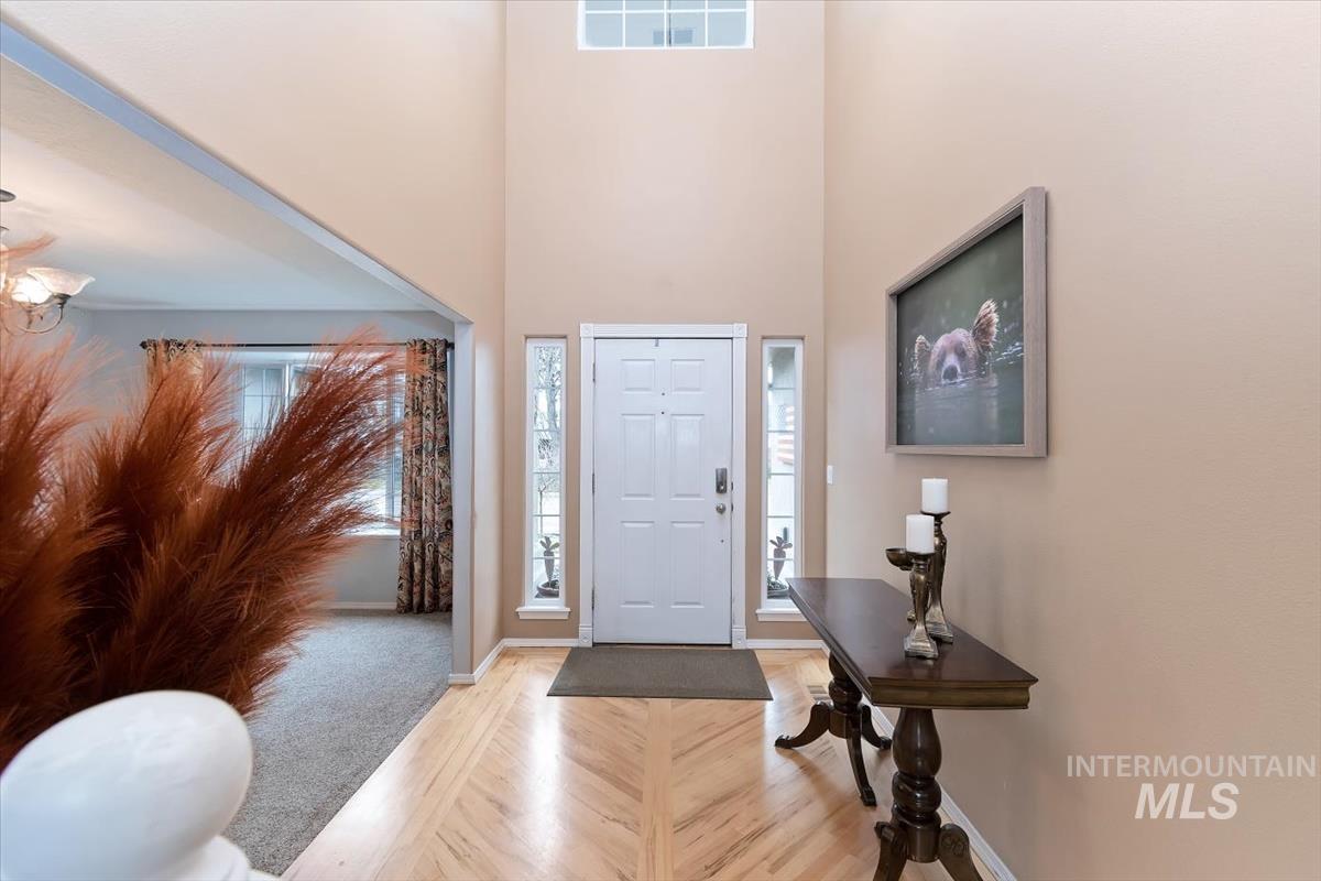 Two-story foyer featuring an arched entryway, natural wood-finish flooring with a herringbone pattern, a multi-pane front door, and a transom window