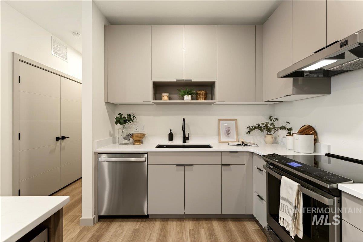 Kitchen with stainless steel appliances, gray cabinetry, open shelves, light wood finished floors, and modern cabinets