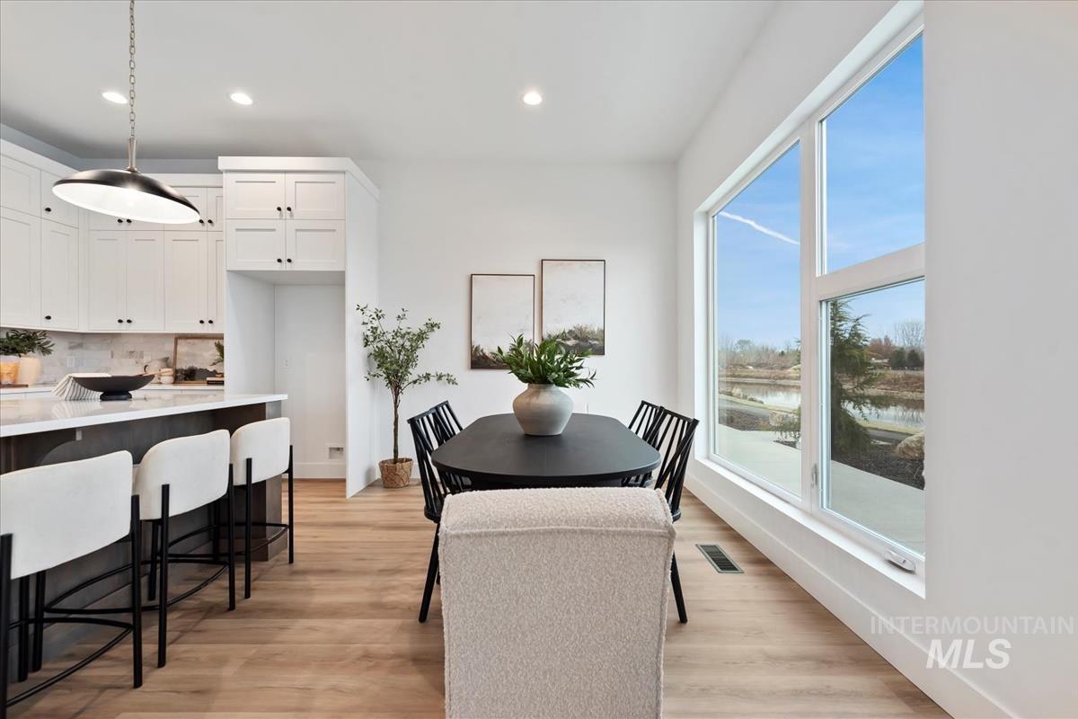 Dining area featuring light wood-type flooring, recessed lighting, and a water view
