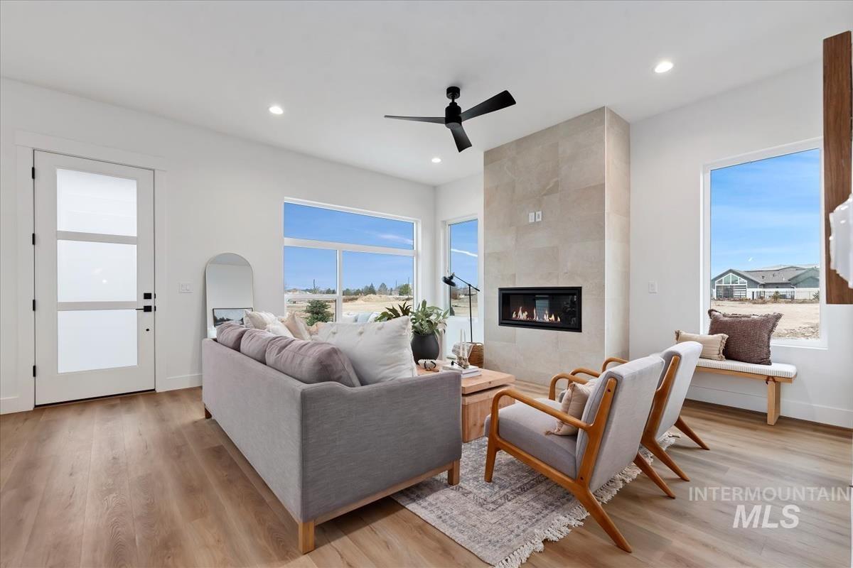 Living area featuring light wood finished floors, a tiled fireplace, ceiling fan, and recessed lighting