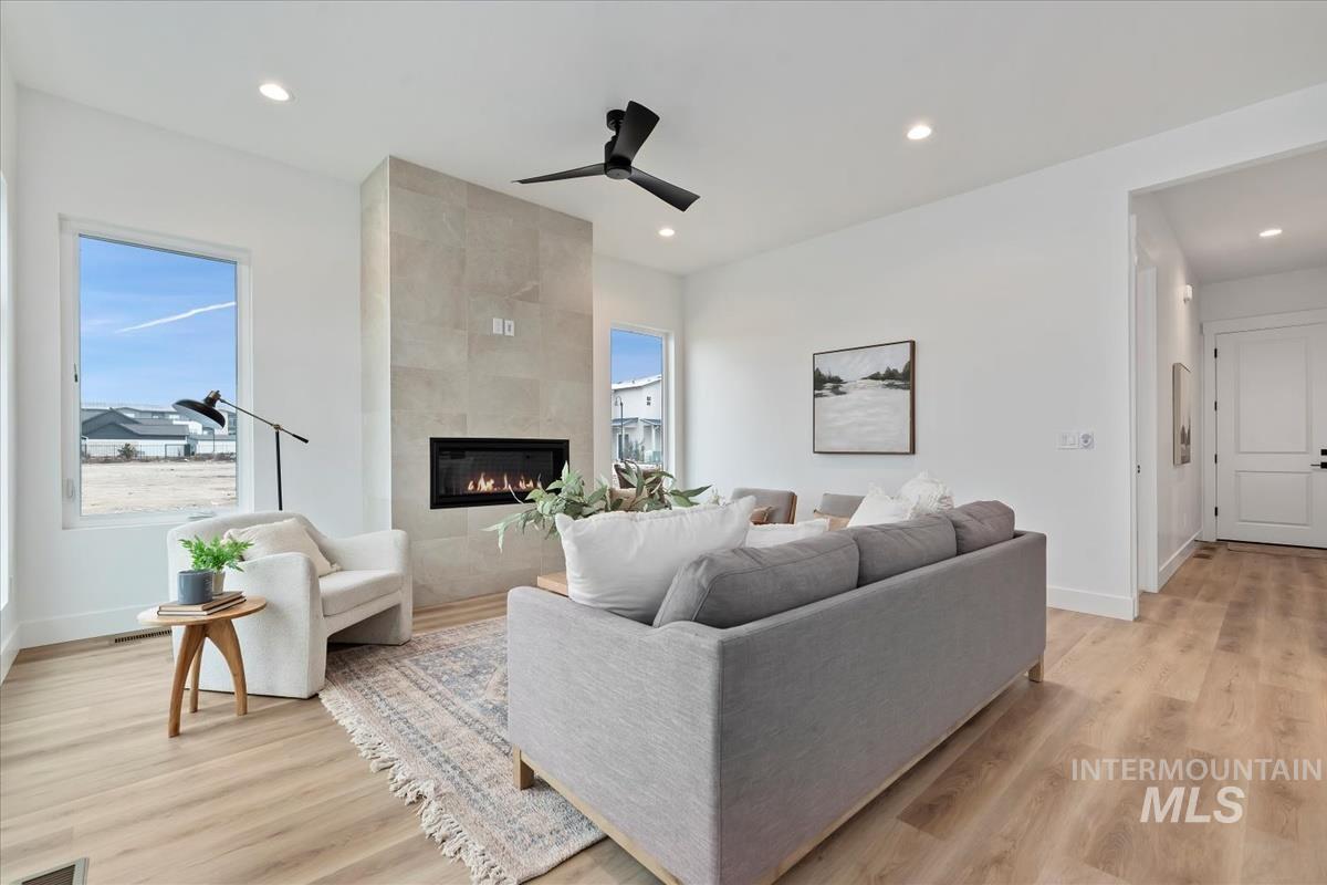 Living area featuring ceiling fan, light wood finished floors, a tile fireplace, and recessed lighting