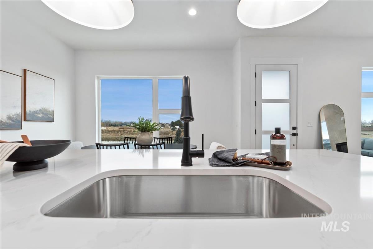 Kitchen view of light stone counters and recessed lighting