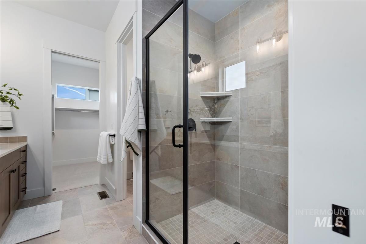 Full bath with vanity, a walk in closet, and a stall shower