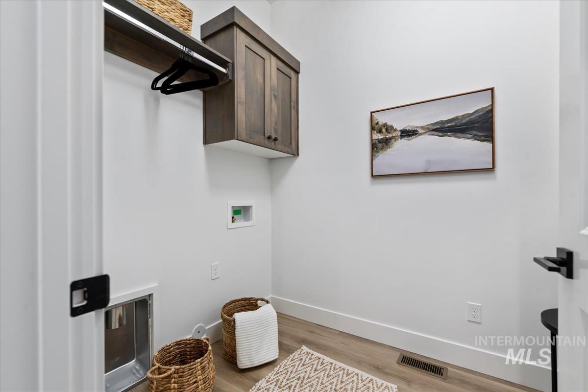 Laundry room featuring light wood-style floors, washer hookup, and cabinet space