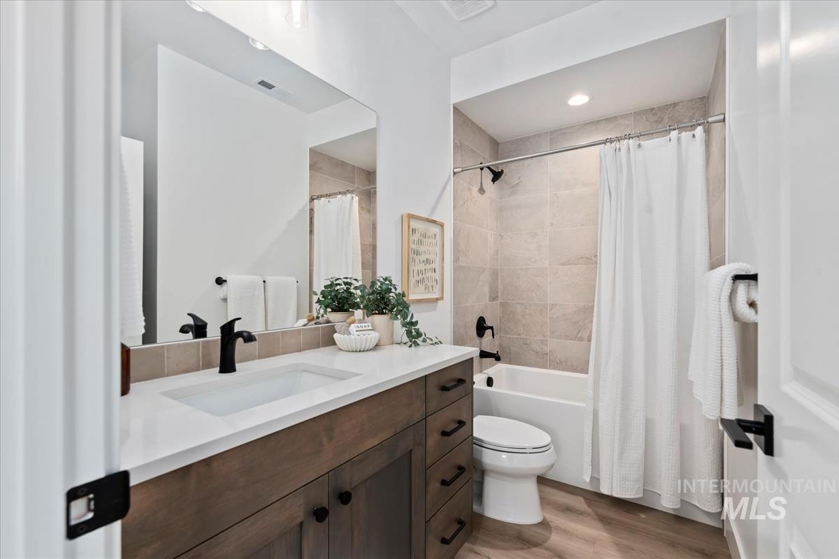 Full bathroom with vanity, light wood-type flooring, and shower / bath combination with curtain