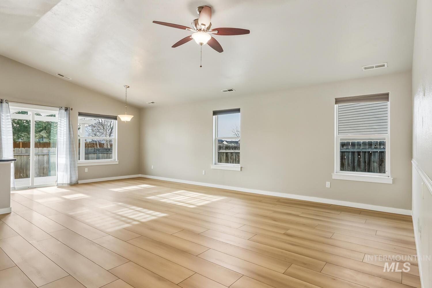 Spare room featuring a ceiling fan, light wood finished floors, vaulted ceiling, and plenty of natural light