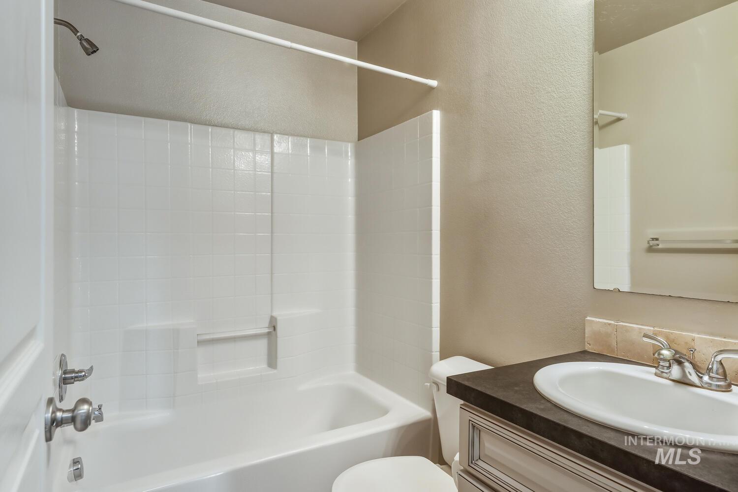 Bathroom featuring a textured wall, shower / tub combination, and vanity