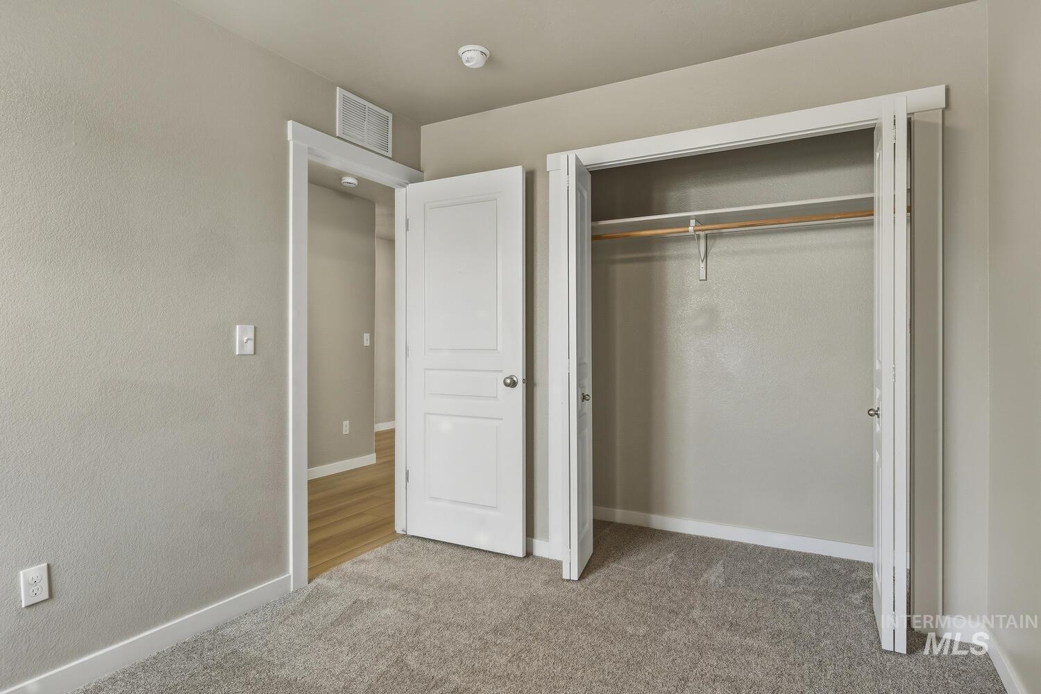 Unfurnished bedroom with light carpet and a closet