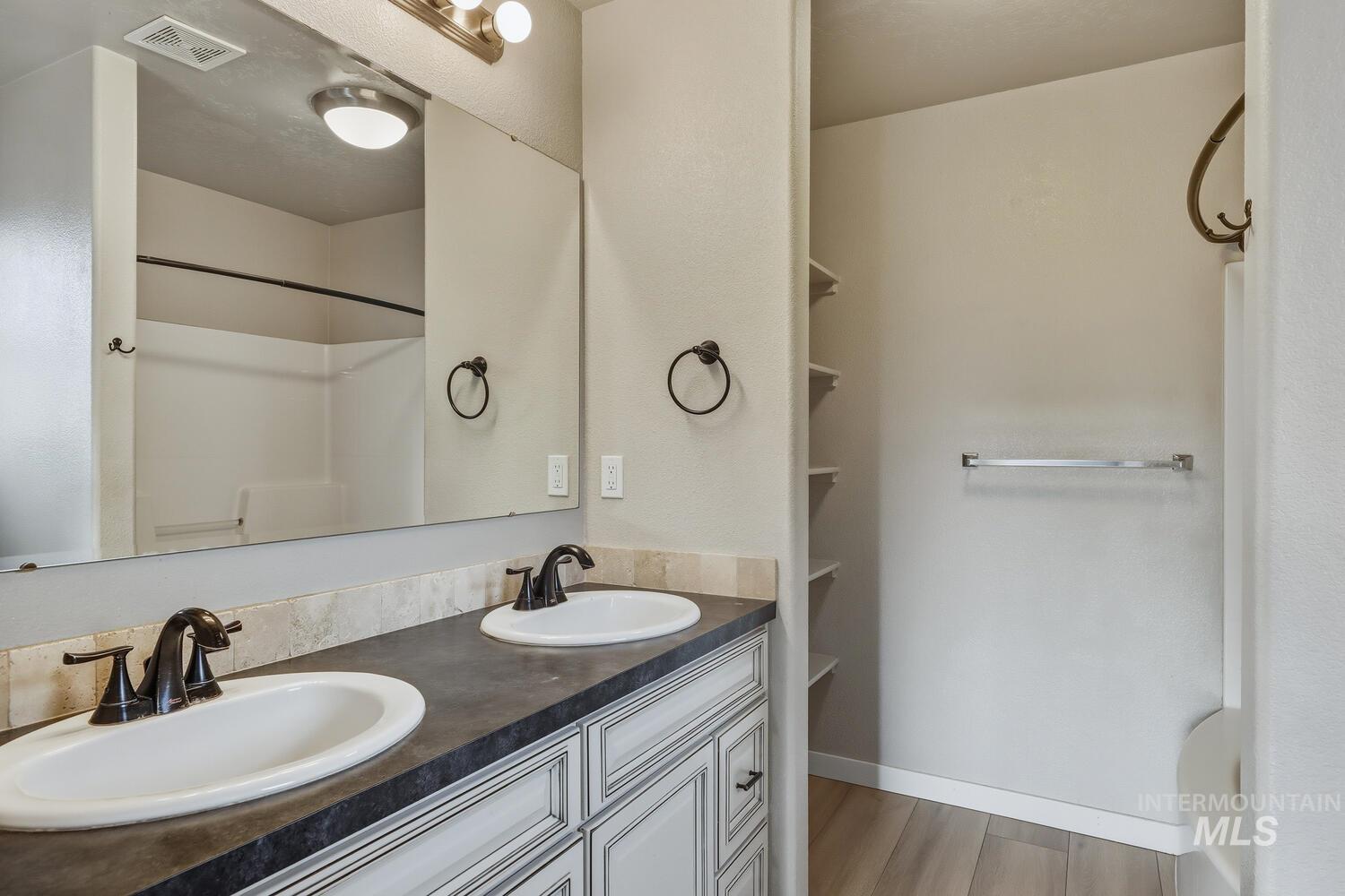 Bathroom featuring double vanity, light wood finished floors, and tub / shower combination