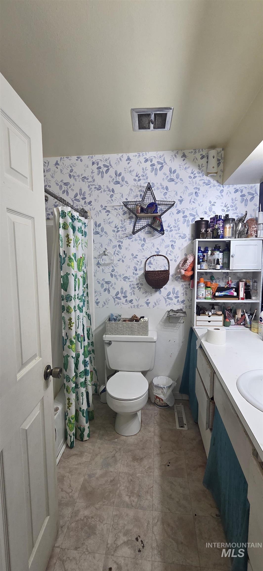 Bathroom with wallpapered walls, vanity, and a shower with shower curtain