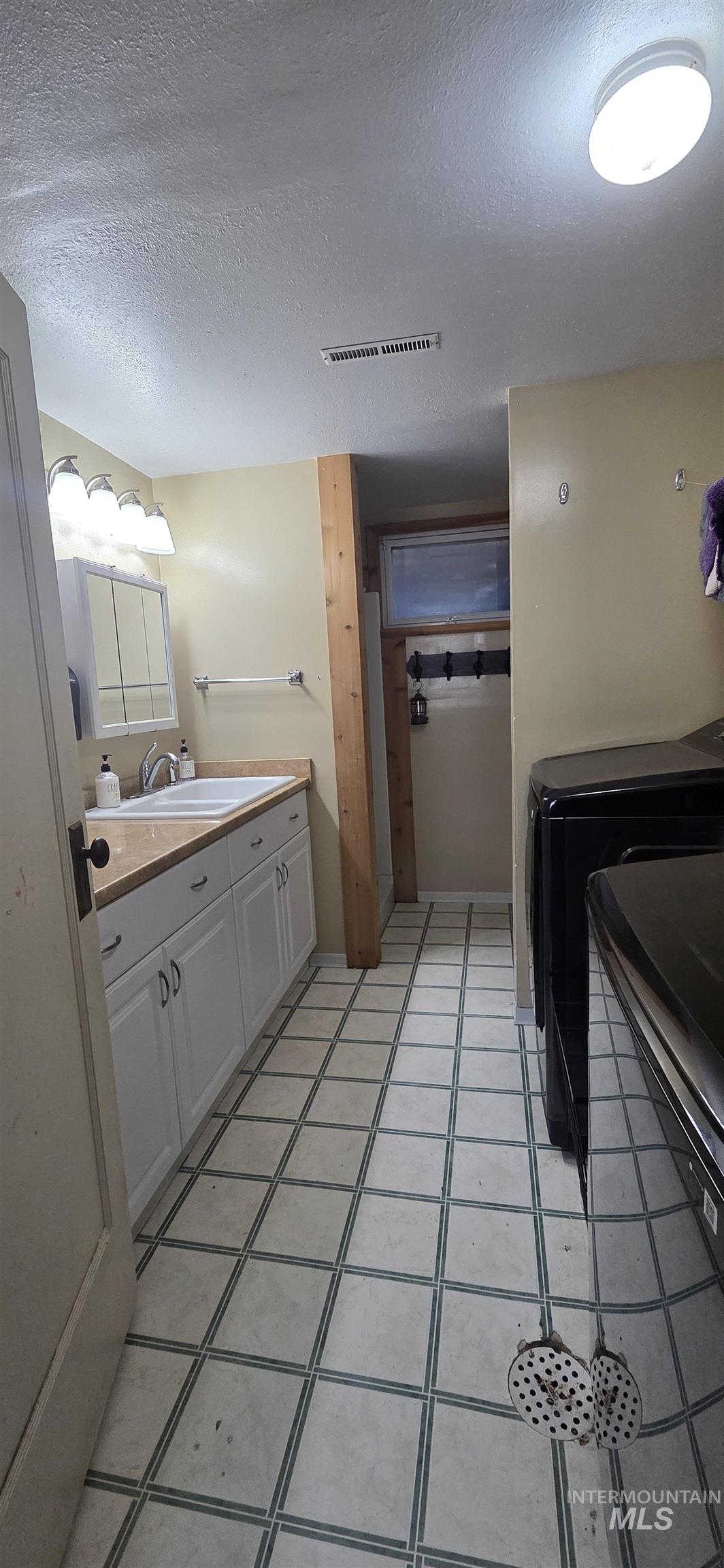 Bathroom featuring vanity, a textured ceiling, and light tile patterned flooring
