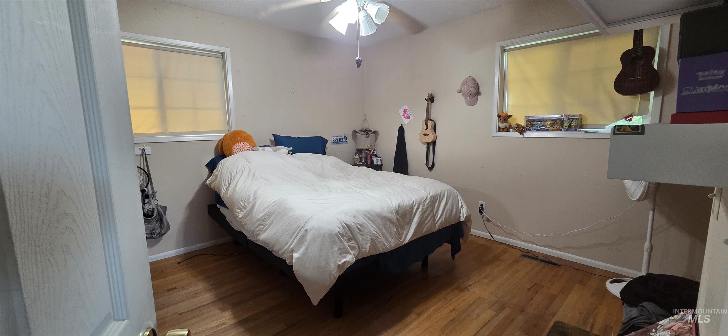 Bedroom featuring wood finished floors, a ceiling fan, and multiple windows