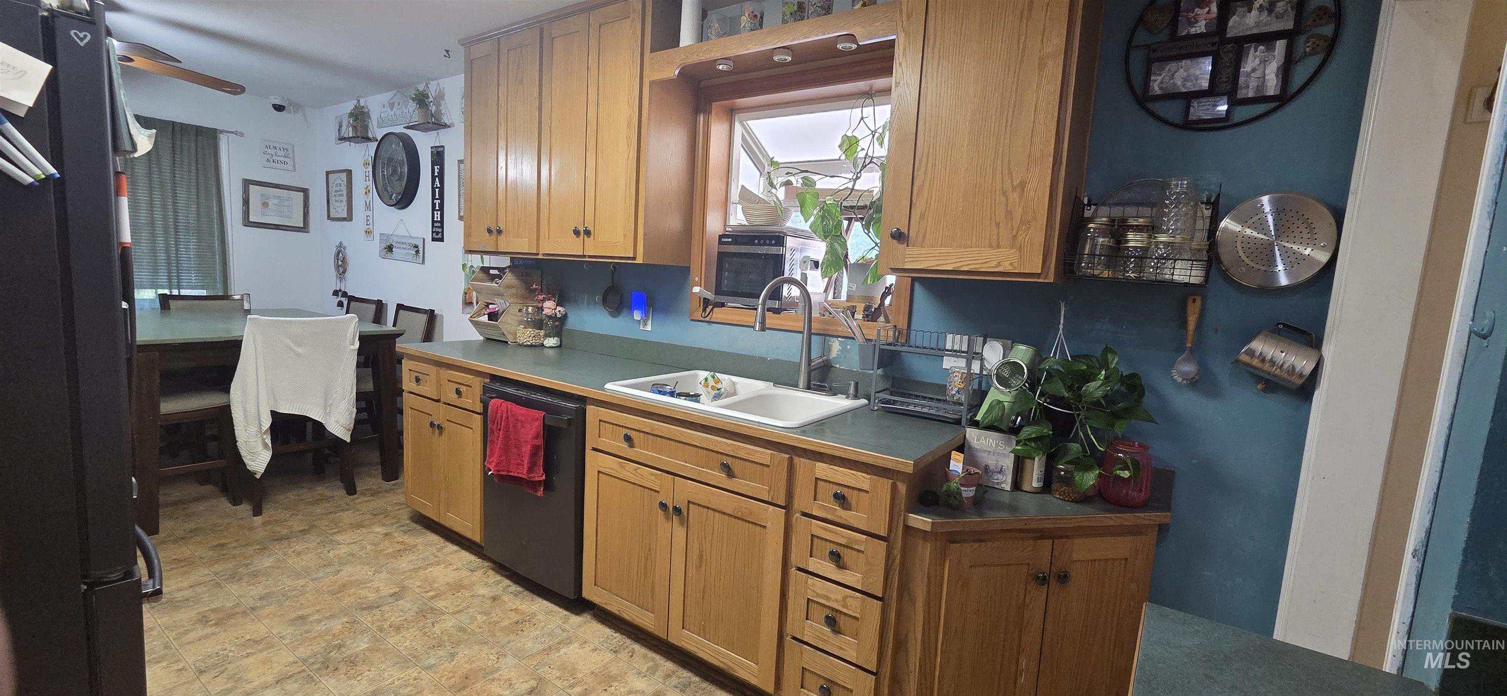 Kitchen featuring dishwasher, refrigerator, a ceiling fan, and dark countertops