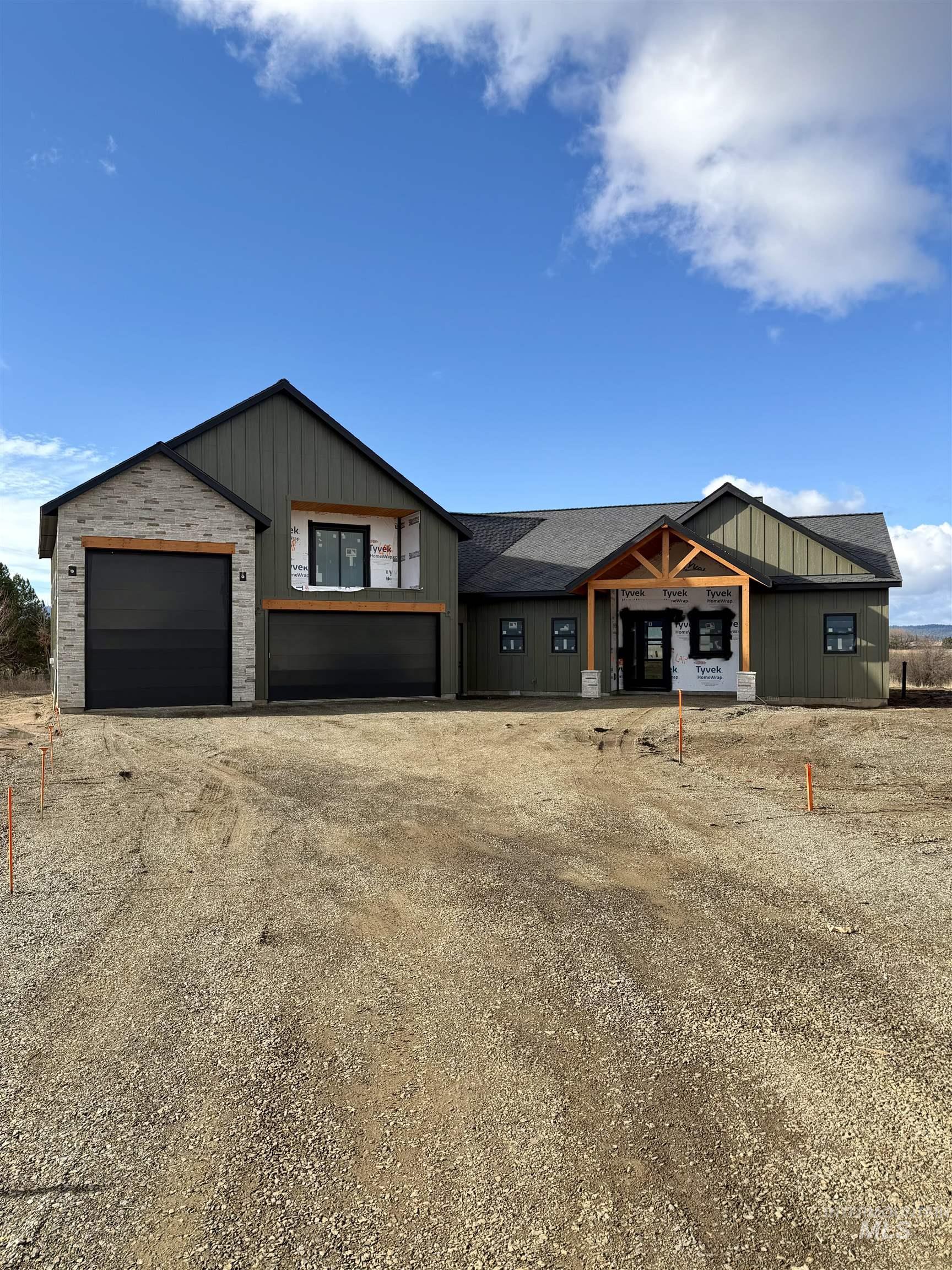 View of front facade with dirt driveway, board and batten siding, and covered porch