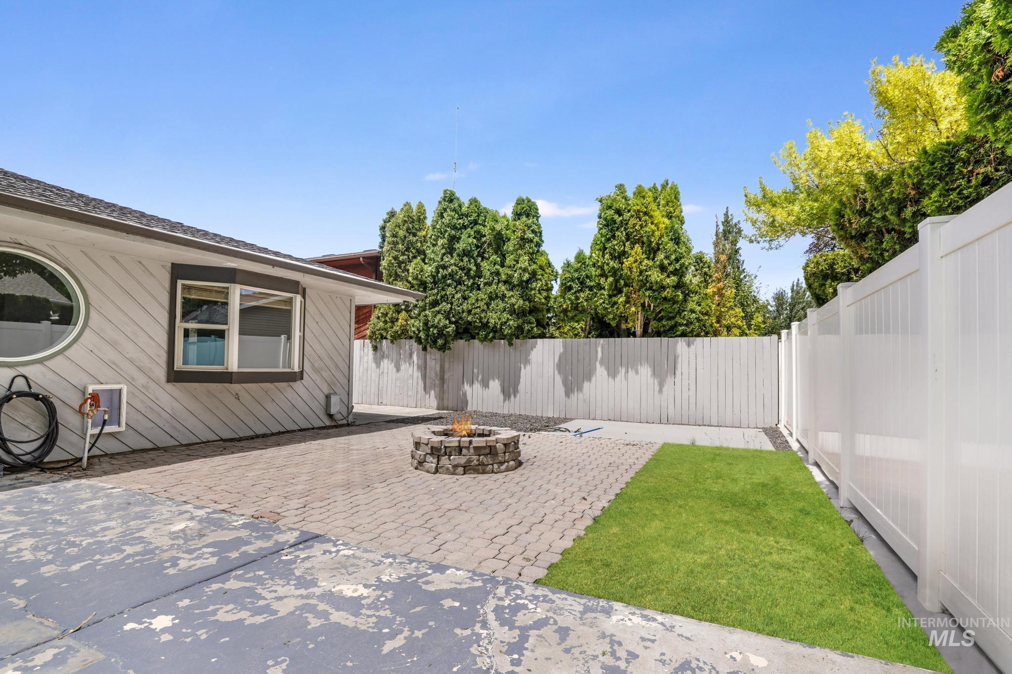 Fenced backyard with a fire pit and a patio