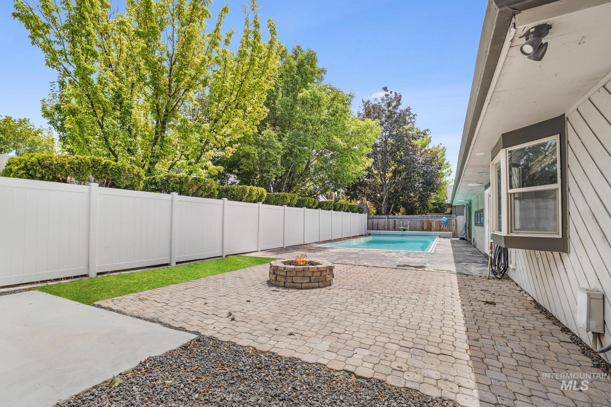 View of pool with an outdoor fire pit, a patio area, and a fenced backyard