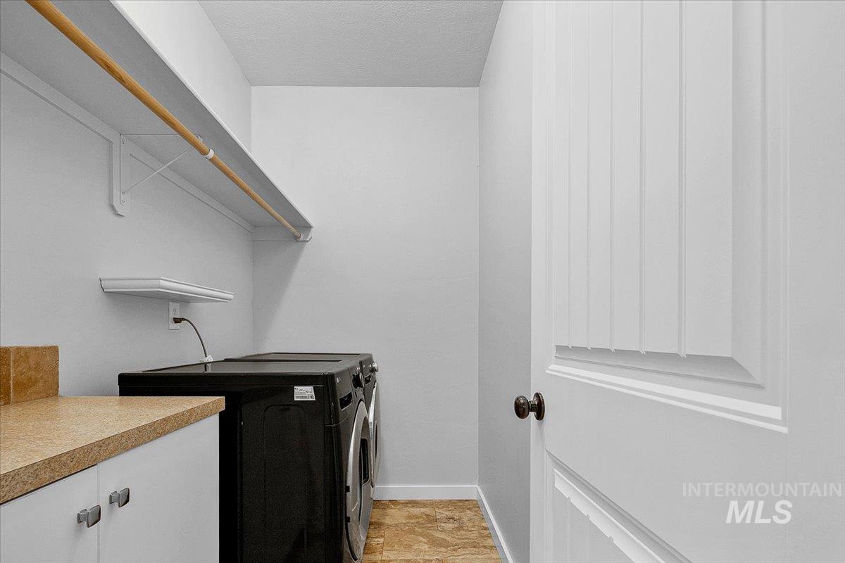 Laundry area featuring a textured ceiling, washer and dryer, and cabinet space