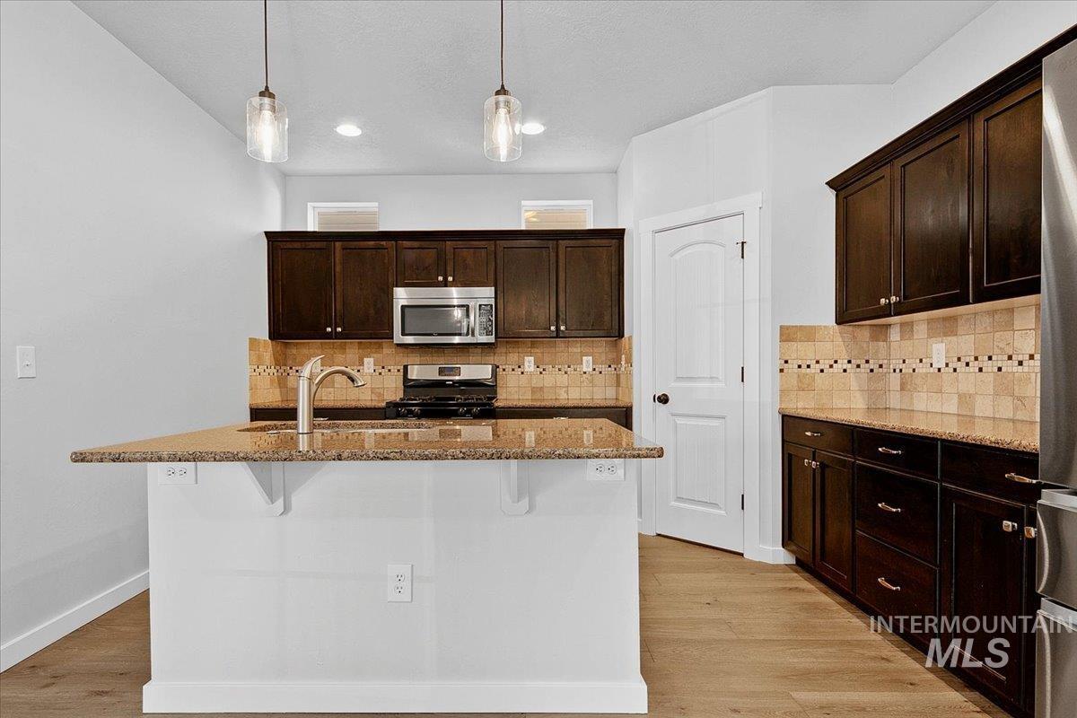 Kitchen featuring dark wood finish cabinetry, light stone counters, and a breakfast bar area