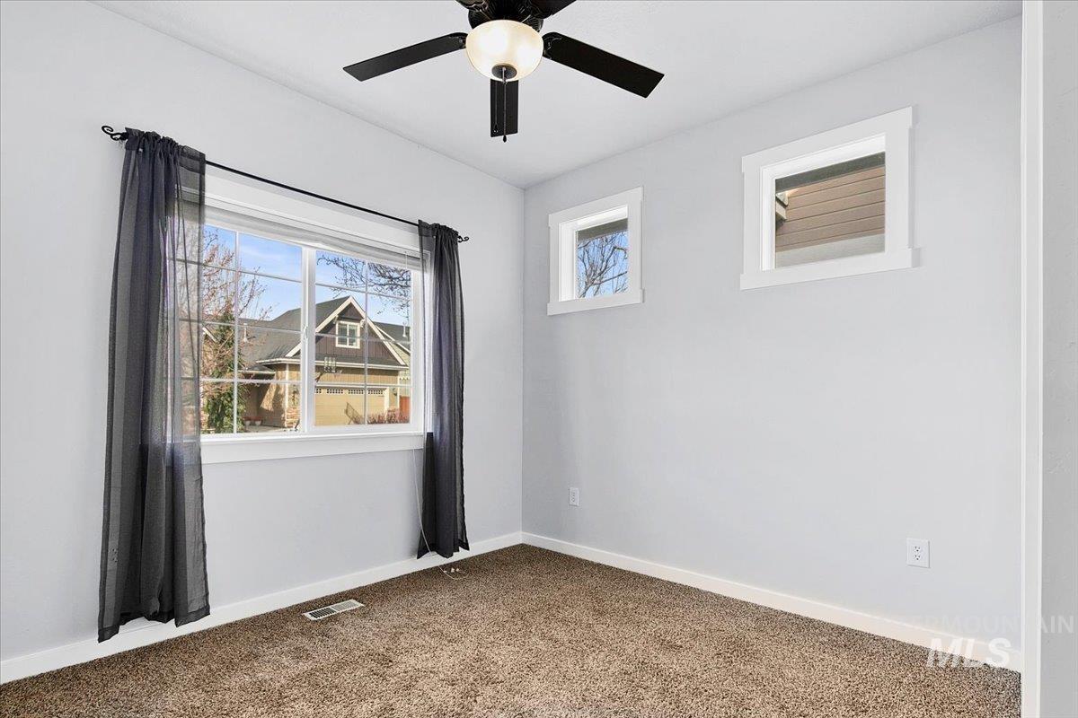 Empty room featuring dark colored carpet and ceiling fan