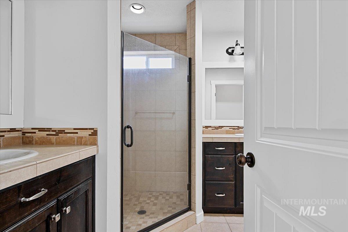 Bathroom with vanity, a stall shower, and backsplash