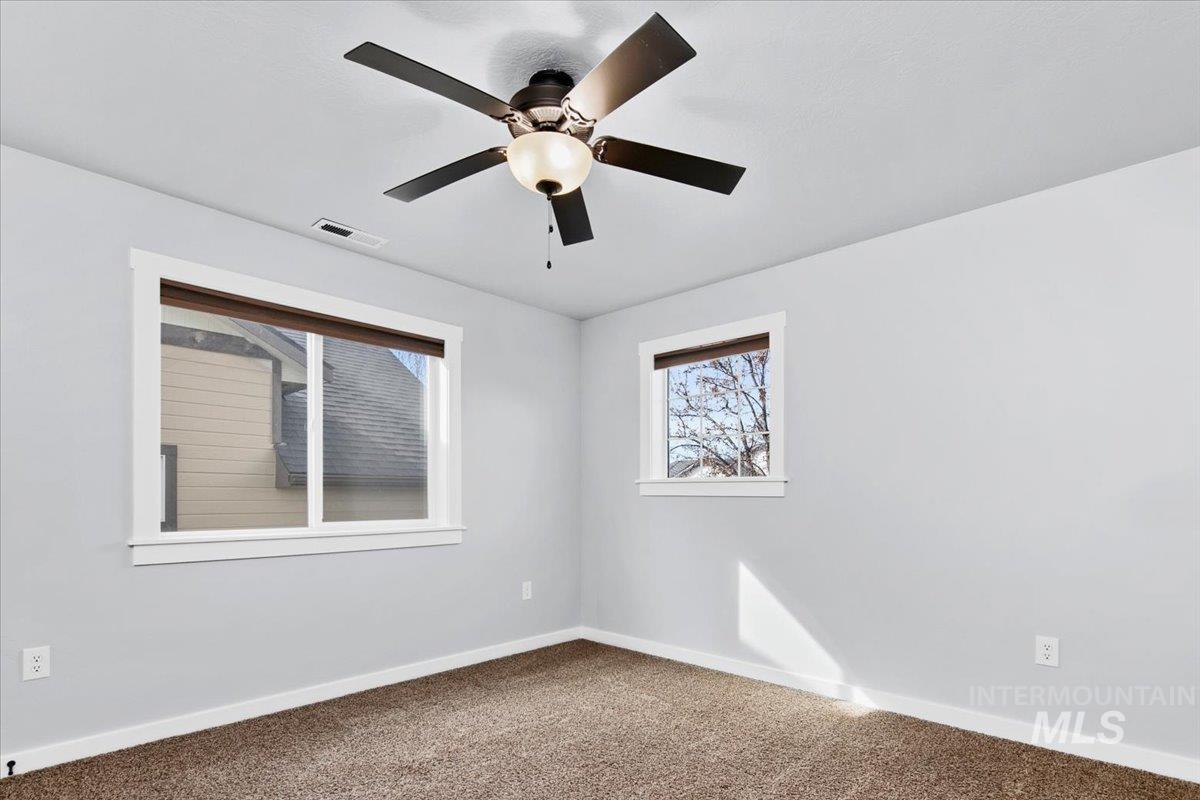 Spare room with healthy amount of natural light, dark carpet, and a ceiling fan