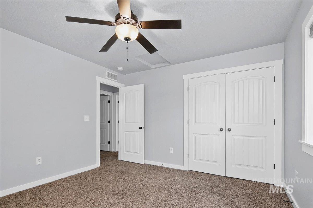 Unfurnished bedroom with carpet, a closet, and a ceiling fan