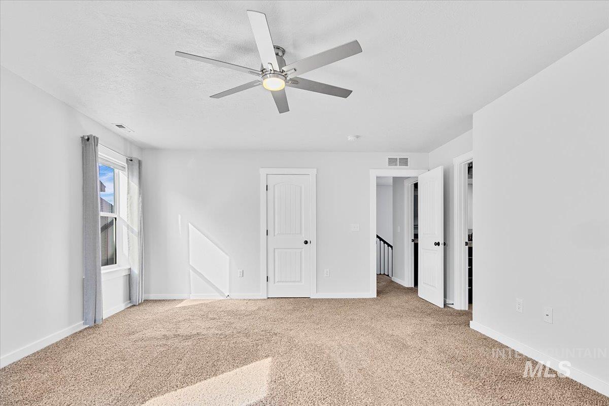 Unfurnished bedroom with ceiling fan, light carpet, a closet, and a textured ceiling